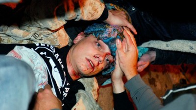 10월 25일 밤 경찰이 쏜 물체에 머리를 맞아 피를 흘리고 있는스캇올슨(Scott Olsen)을 동료들이 병원으로 옮기고 있다. 